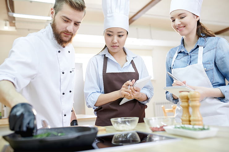 Three chefs working on a dish.