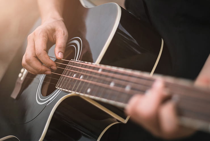 A close up of man's hands holding a guitar.